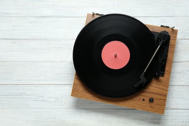Turntable with vinyl record on white wooden background, top view. Space for text