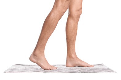 Man standing on soft bath mat against white background, closeup