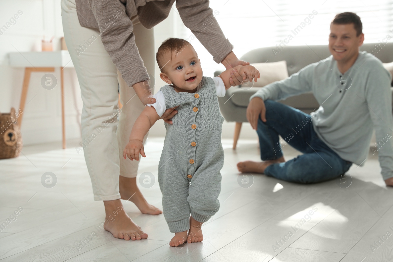 Photo of Mother supporting her baby daughter while she learning to walk at home