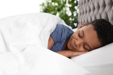 Photo of Cute little African-American boy sleeping in bed