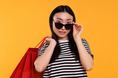 Photo of Beautiful woman with shopping bags on yellow background