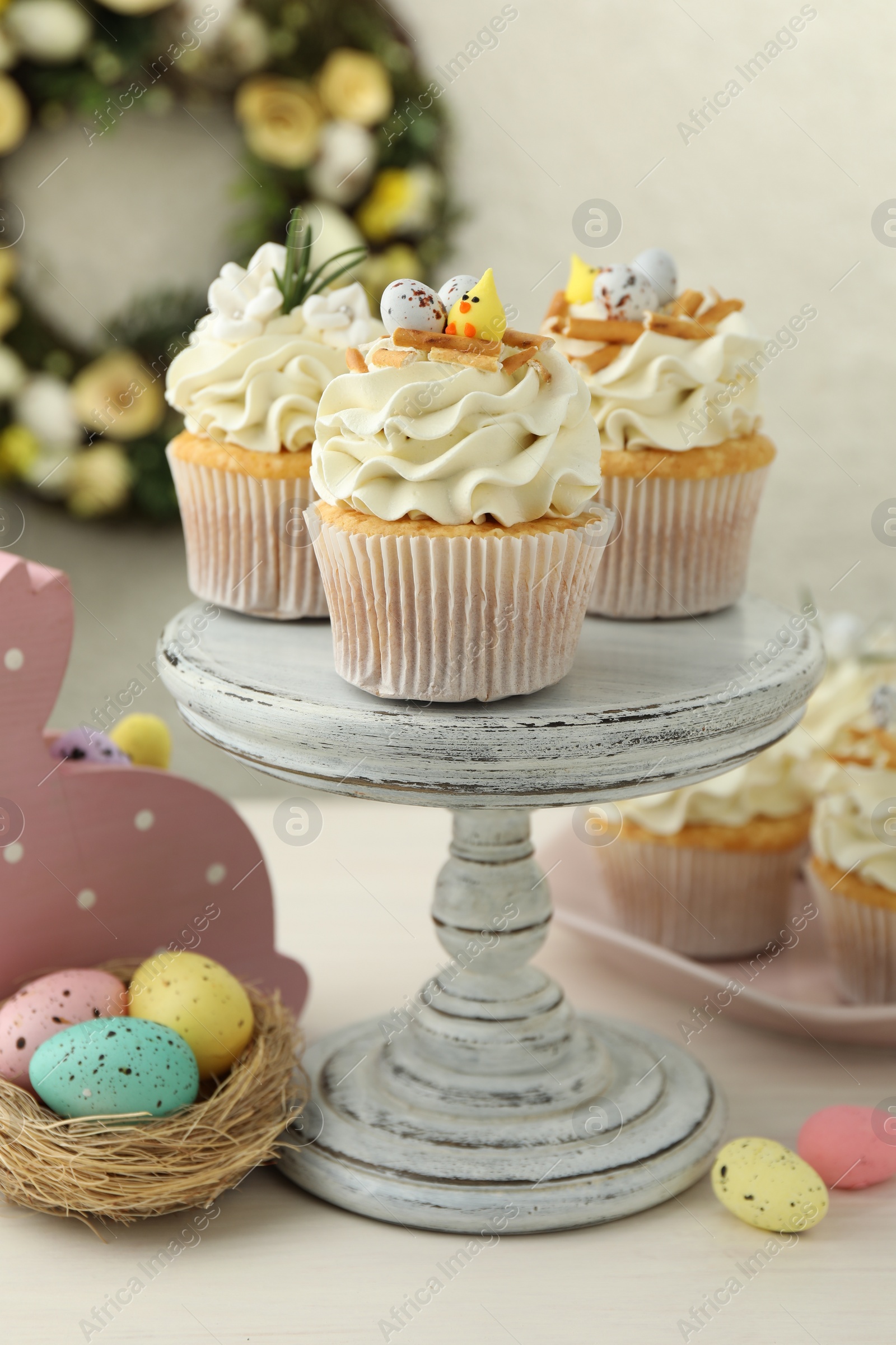 Photo of Tasty Easter cupcakes with vanilla cream and festive decor on light wooden table