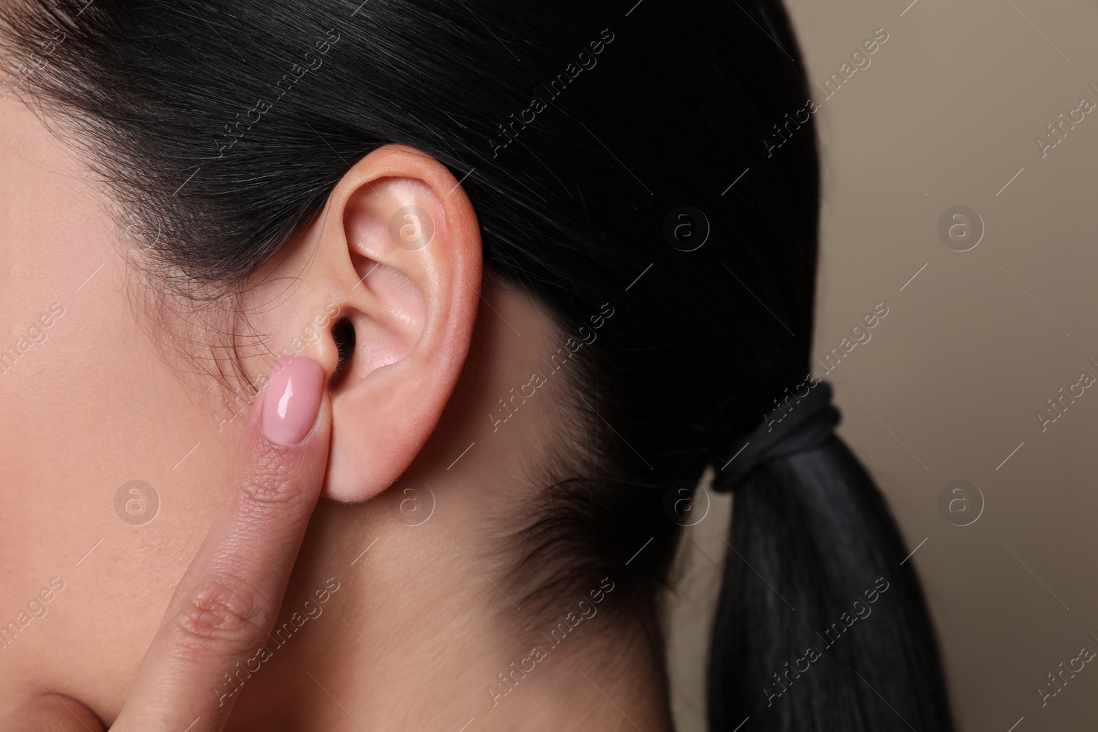 Photo of Woman pointing at her ear on grey background, closeup
