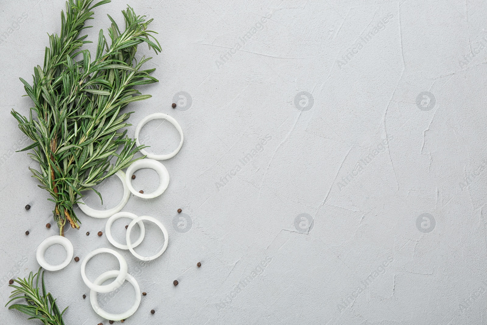 Photo of Fresh rosemary, onion and pepper on light grey table. Space for text