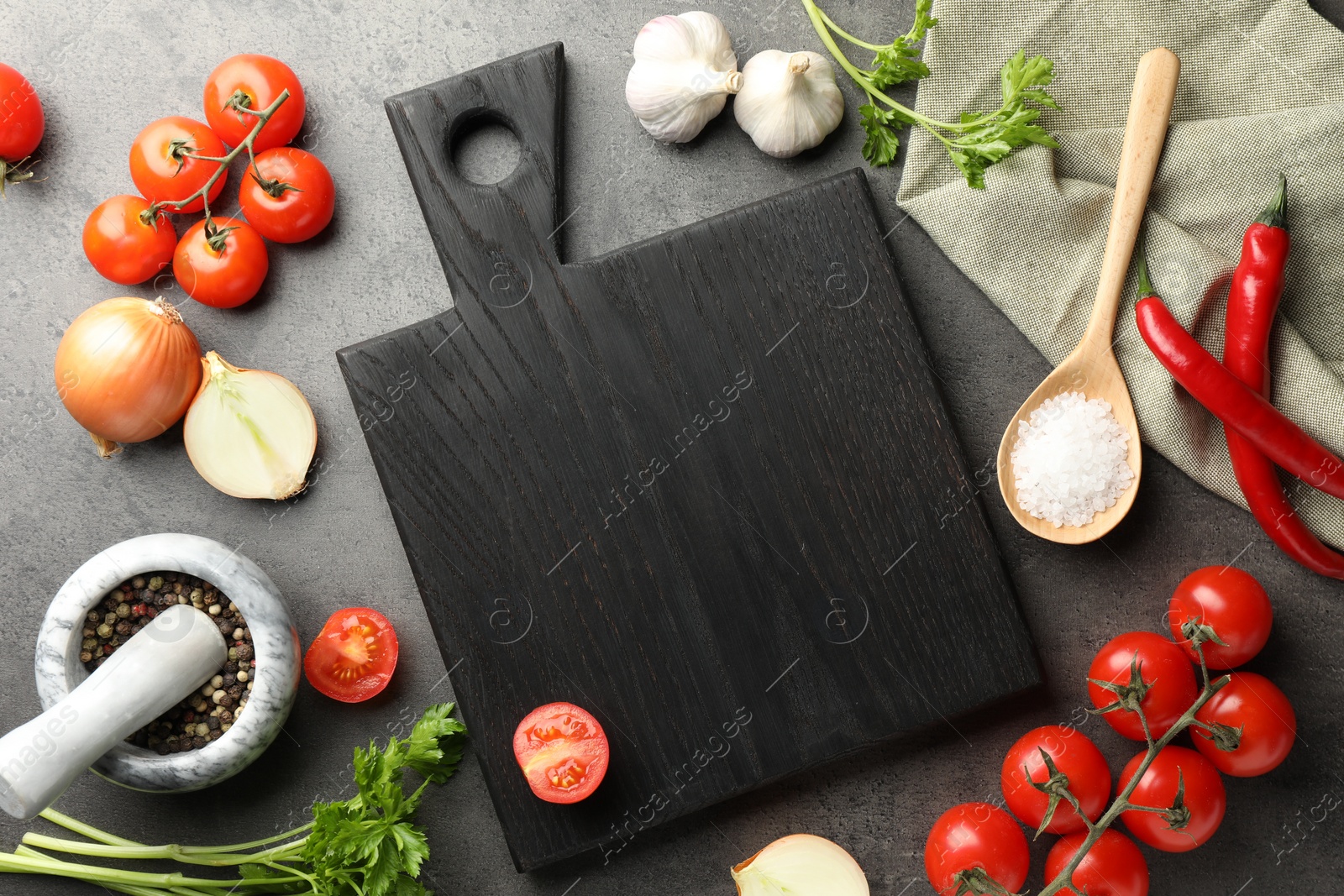 Photo of Flat lay composition with black wooden cutting board and products on dark textured table