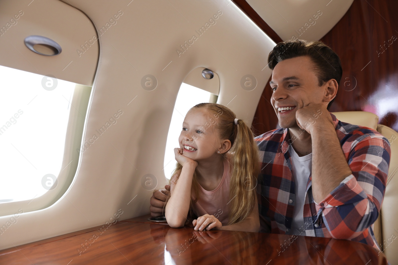 Photo of Father with daughter looking out window in airplane during flight