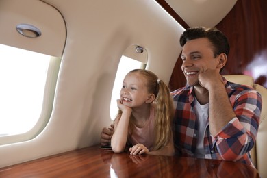 Photo of Father with daughter looking out window in airplane during flight