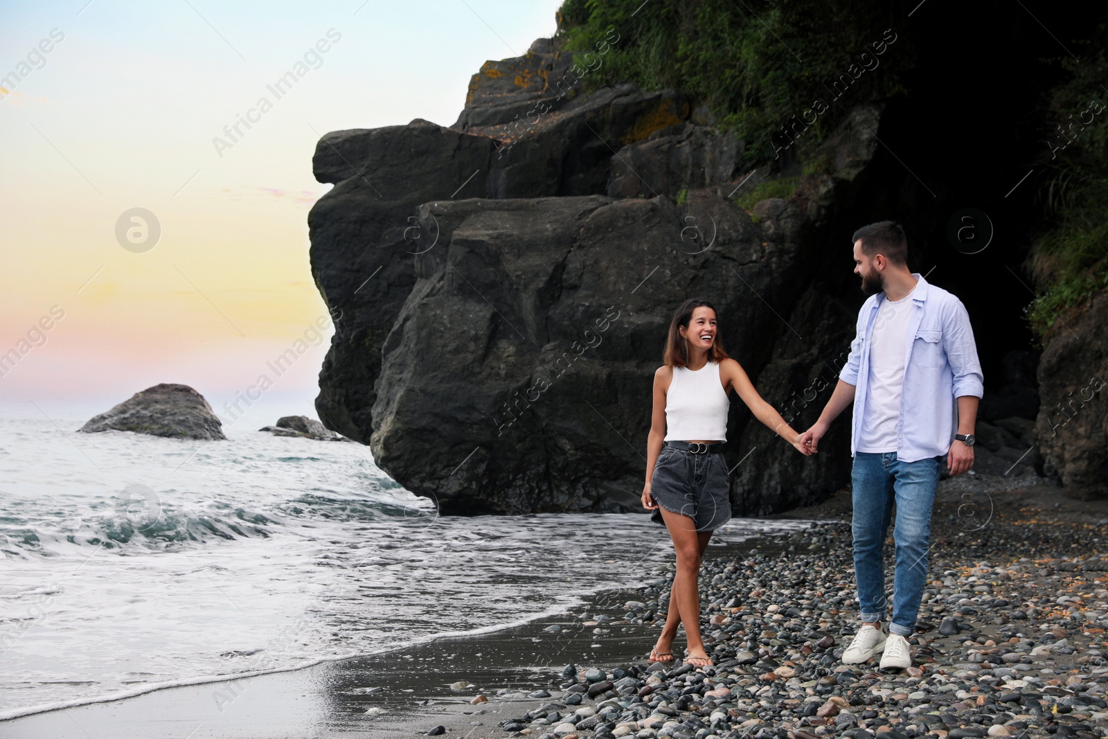 Photo of Happy young couple walking on beach near sea. Space for text