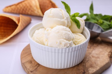 Photo of Bowl of ice cream and mint leaves on white table, closeup
