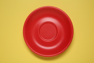 Photo of One red ceramic plate on yellow background, top view