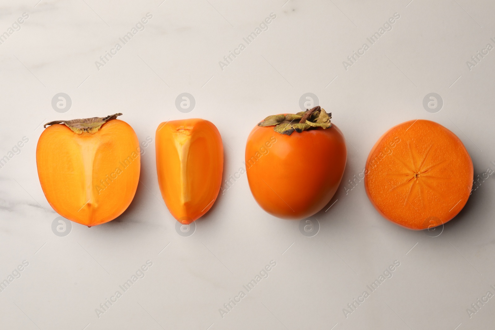 Photo of Delicious ripe persimmons on white marble table, flat lay