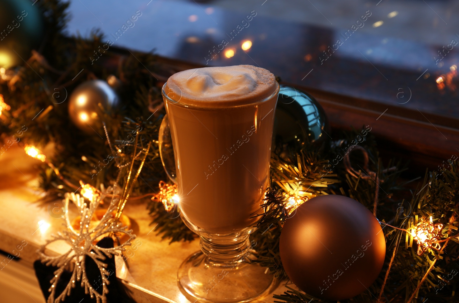 Photo of Glass of delicious hot cocoa and Christmas decoration on windowsill