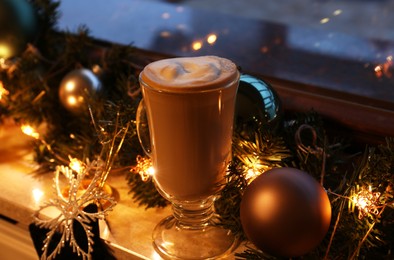 Photo of Glass of delicious hot cocoa and Christmas decoration on windowsill