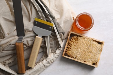 Photo of Different beekeeping tools and jar of honey on white table, flat lay
