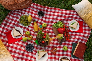 Photo of Picnic blanket with delicious snacks, top view
