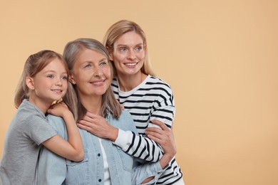 Photo of Three generations. Happy grandmother, her daughter and granddaughter on beige background, space for text