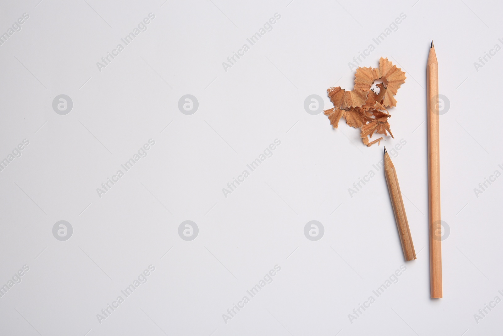 Photo of Sharp graphite pencils and shavings on white background, top view. Space for text