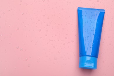 Photo of Wet tube of face cleansing product on pink background, top view. Space for text