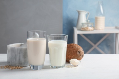Glasses with coconut and oat milk on wooden table