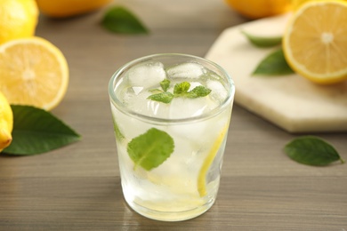 Cool freshly made lemonade in glass on wooden table, closeup