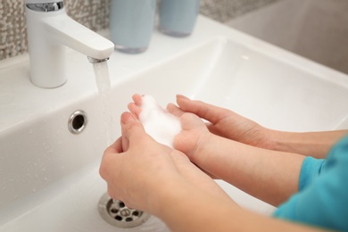Photo of Mother and daughter washing hands in bathroom at home, closeup
