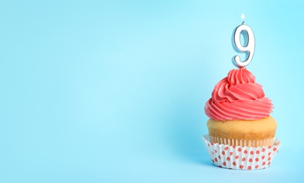 Photo of Birthday cupcake with number nine candle on blue background, space for text