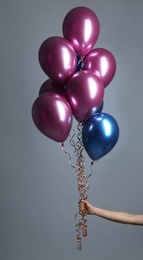 Photo of Woman holding bunch of balloons on grey background, closeup
