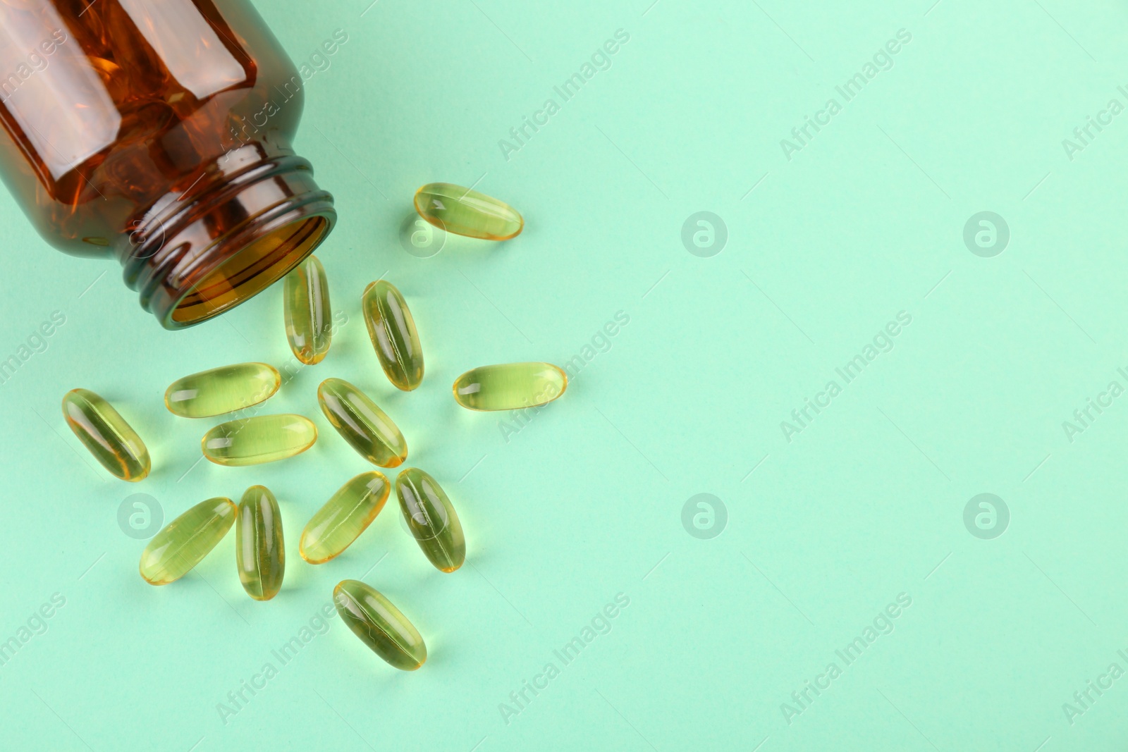 Photo of Bottle and vitamin capsules on turquoise background, top view. Space for text