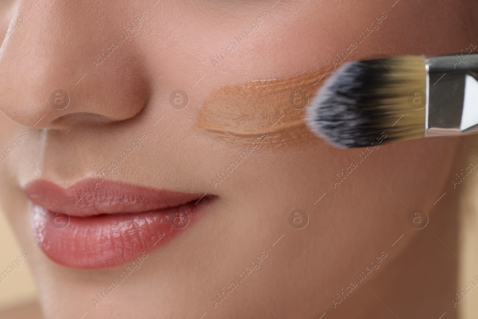 Photo of Woman applying foundation on face with brush, closeup