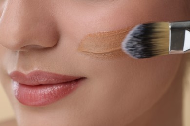 Woman applying foundation on face with brush, closeup