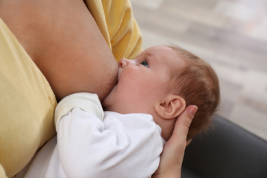 Young woman breast feeding her little baby at home, closeup