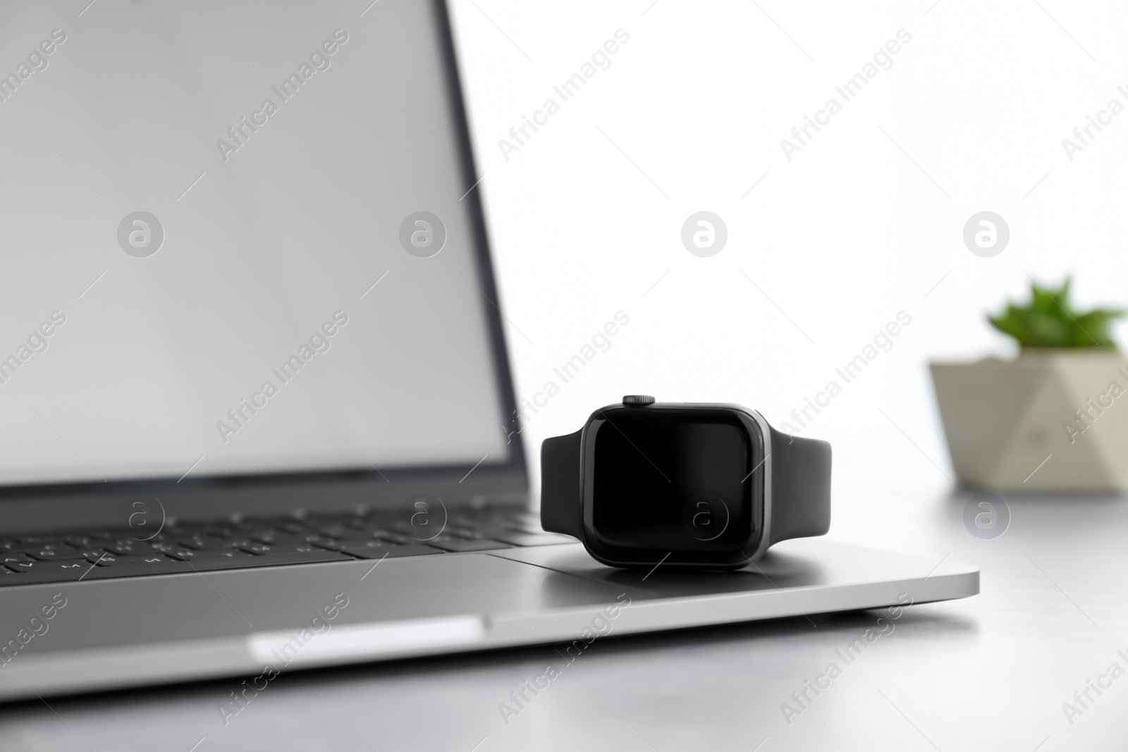 Stylish smart watch and laptop on grey table Photo of Stylish smart watch and laptop on grey table
