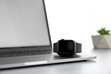 Photo of Stylish smart watch and laptop on grey table