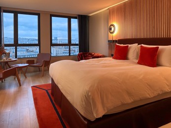 Photo of Stylish hotel room interior with large bed, lamp and table