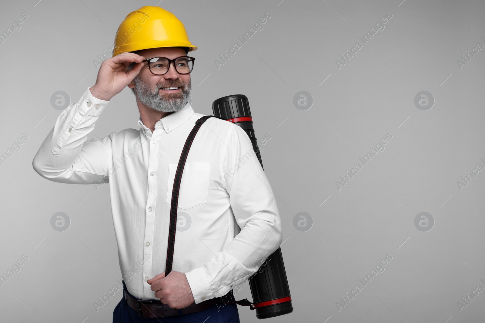 Photo of Architect in hard hat with drawing tube on grey background. Space for text