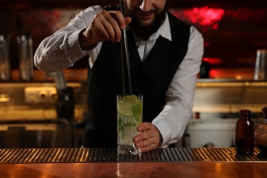 Photo of Bartender making fresh alcoholic cocktail at bar counter, closeup