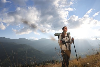 Tourist with backpack and trekking poles hiking through mountains, space for text