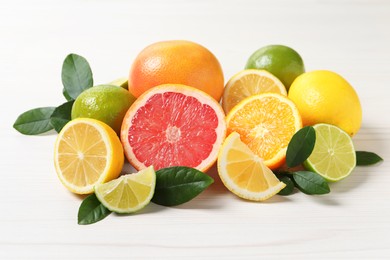 Photo of Different cut and whole citrus fruits on white wooden table