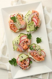 Tasty canapes with salmon served on white wooden table, top view