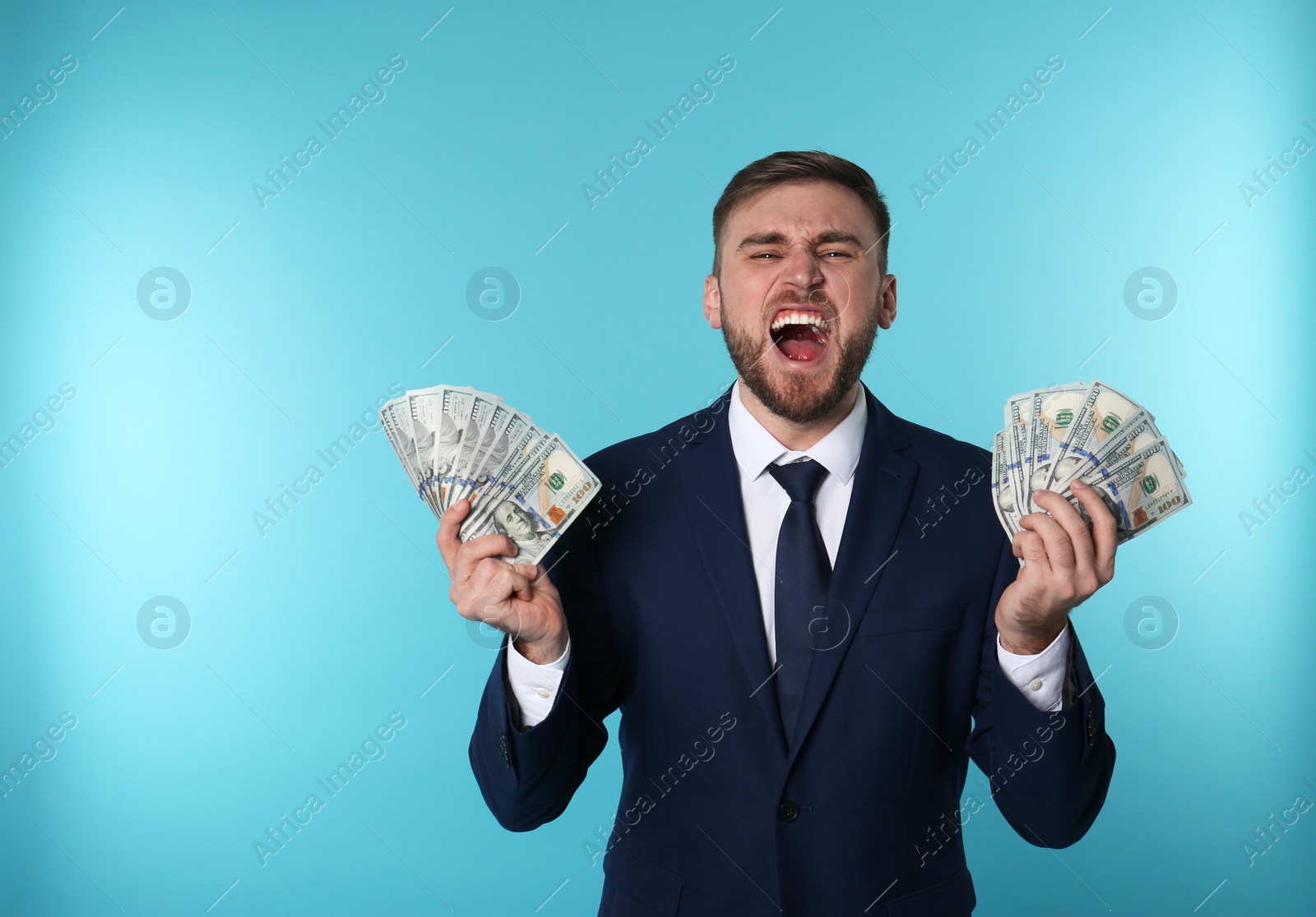 Photo of Portrait of emotional young businessman with money on color background