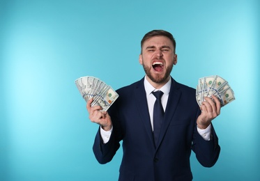 Photo of Portrait of emotional young businessman with money on color background