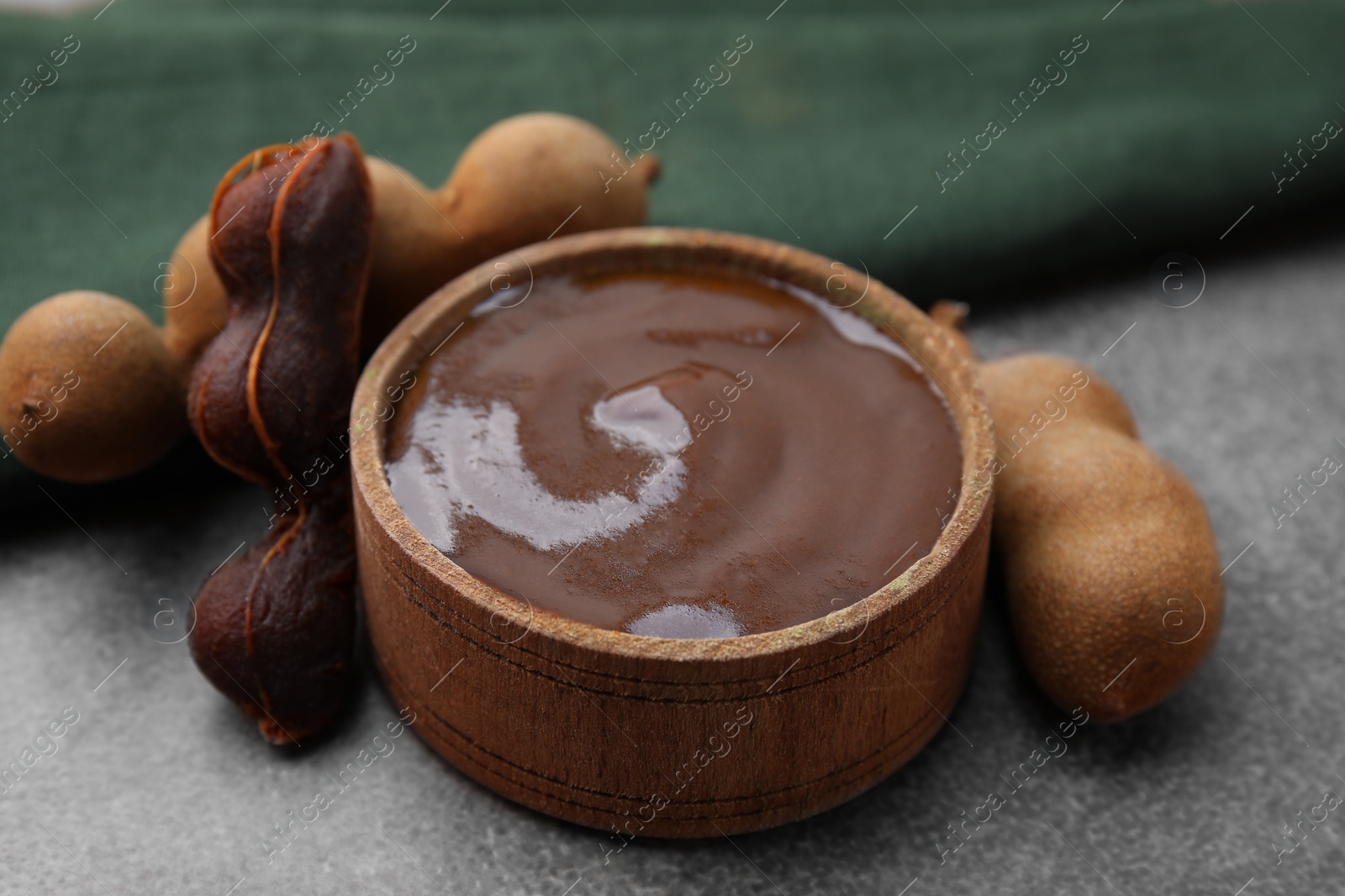 Bowl of tamarind sauce and fresh pods on brown table, closeup Photo of Bowl of tamarind sauce and fresh pods on brown table, closeup