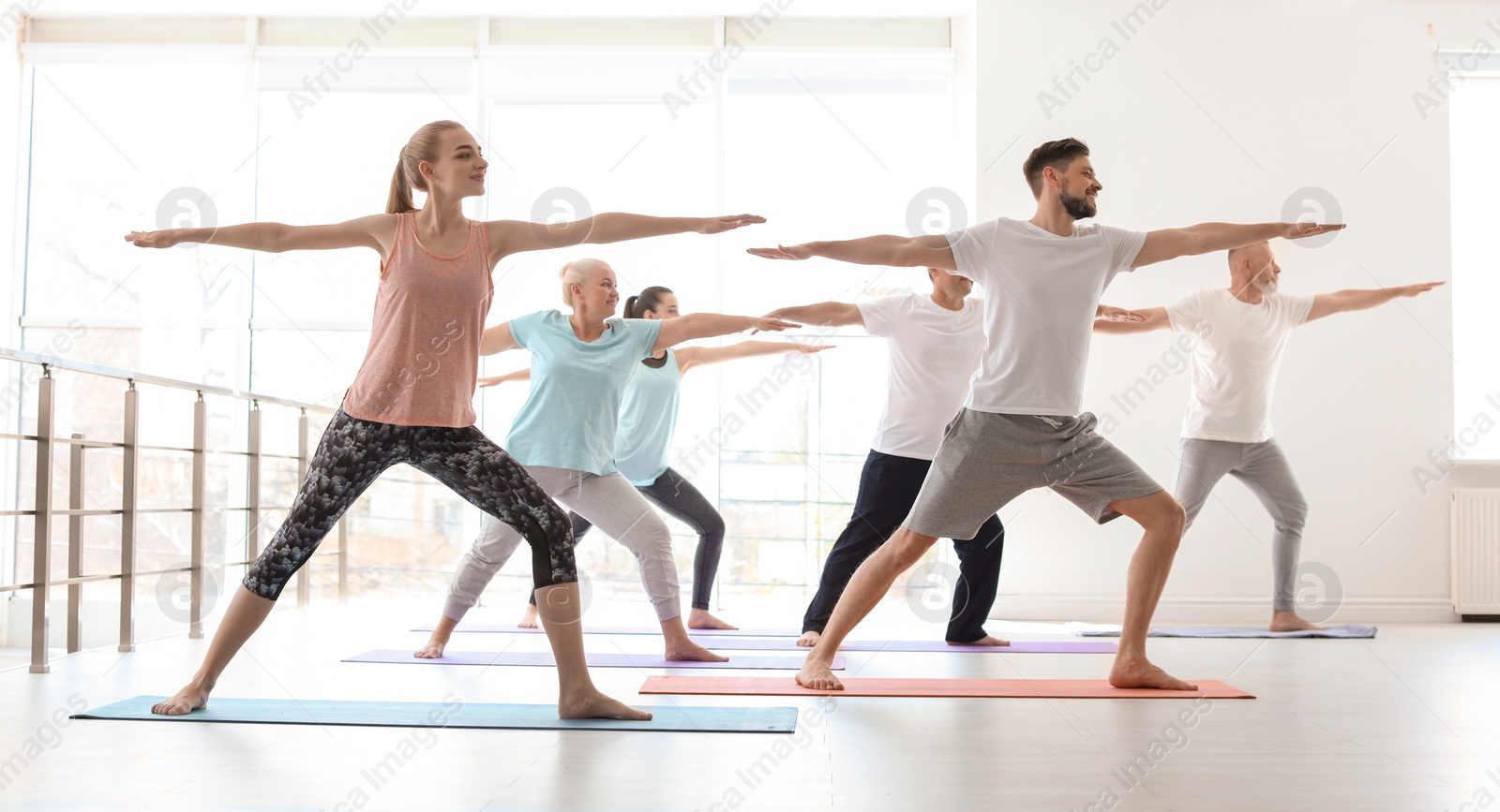 Photo of Group of people in sportswear practicing yoga indoors