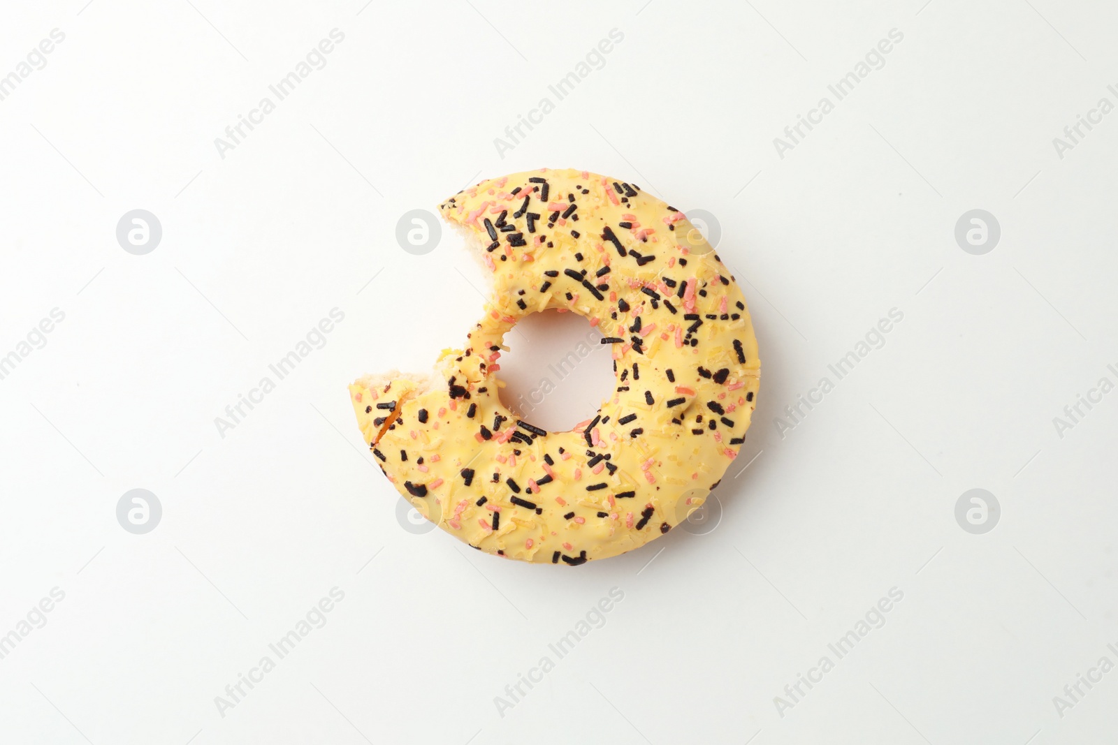 Photo of Delicious yellow glazed donut with bite mark on white background, top view