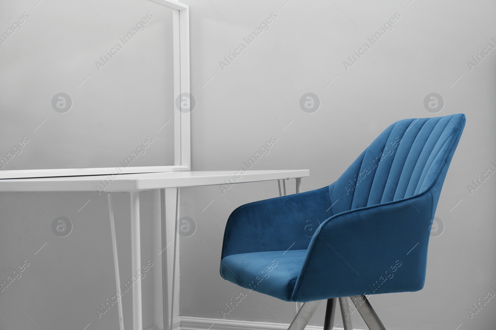 Photo of Blue armchair near white table with mirror in room