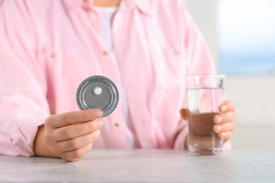 Woman holding blister of emergency contraception pill, closeup