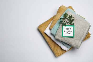 Photo of Recycling concept. Stacked towels and card with plant on white background, top view