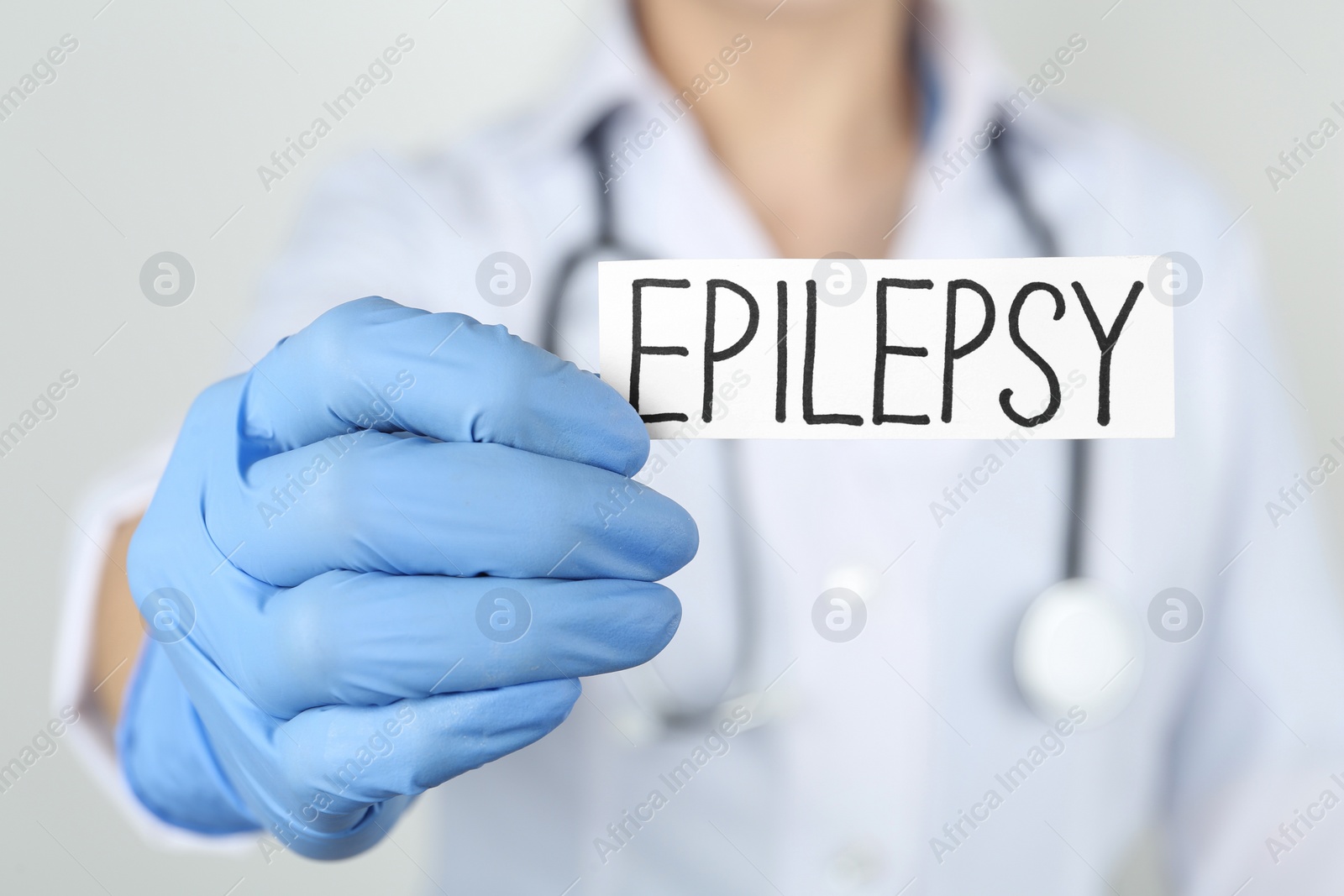 Photo of Doctor holding card with word Epilepsy on light grey background, closeup