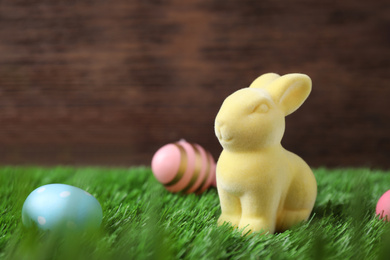 Photo of Easter bunny and painted eggs on green grass, space for text