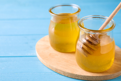 Photo of Tasty aromatic honey on light blue wooden table